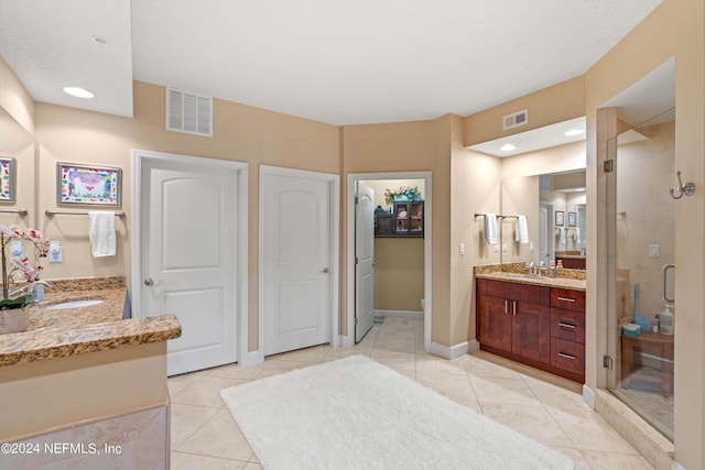 bathroom featuring tile patterned floors, a shower with door, and vanity