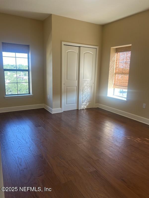 3958 Baymeadows Rd Unit 1204, Jacksonville, FL 32217 - unfurnished bedroom featuring dark wood-type flooring, baseboards, and multiple windows