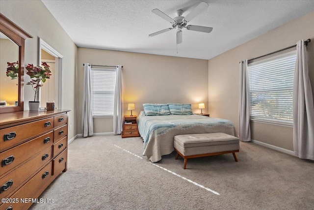 carpeted bedroom featuring ceiling fan, a textured ceiling, and multiple windows