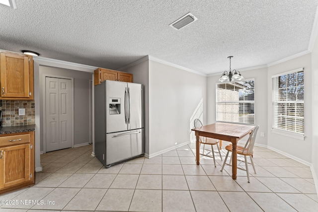 kitchen with hanging light fixtures, light tile patterned floors, ornamental molding, and stainless steel refrigerator with ice dispenser