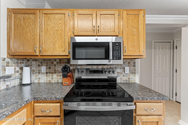 kitchen with backsplash, light tile patterned floors, ornamental molding, and appliances with stainless steel finishes