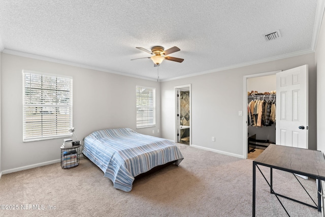 bedroom featuring connected bathroom, ornamental molding, a walk in closet, ceiling fan, and a closet