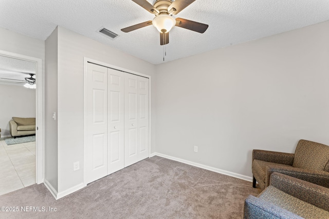 living area featuring ceiling fan, carpet flooring, and a textured ceiling