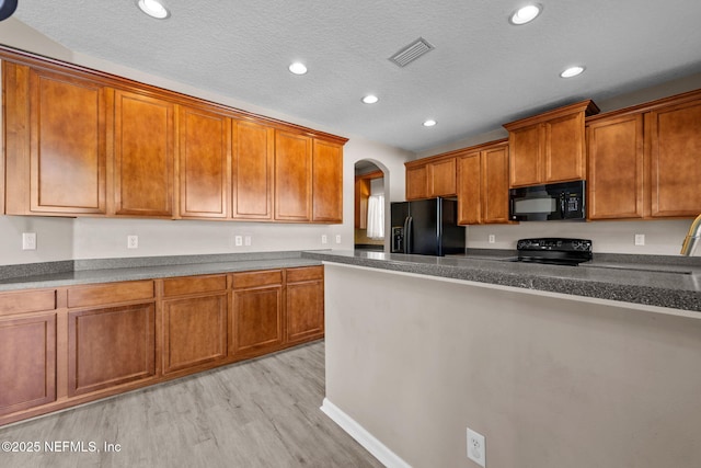 kitchen with black appliances, a textured ceiling, and light hardwood / wood-style floors