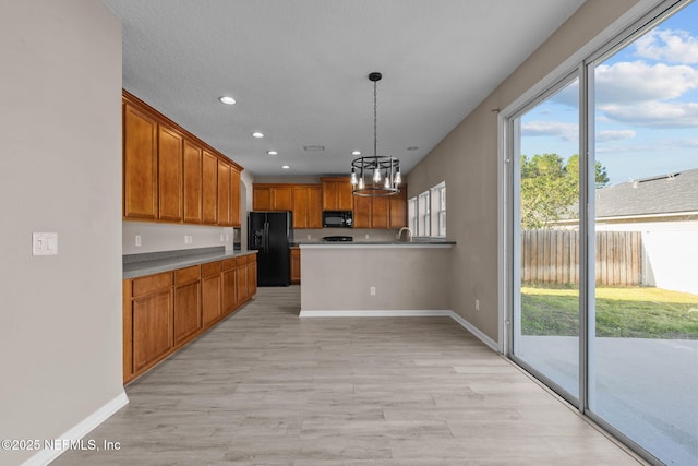 kitchen with light hardwood / wood-style floors, an inviting chandelier, hanging light fixtures, and black appliances