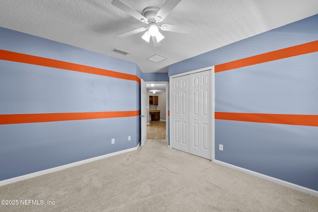 carpeted empty room with ceiling fan and a textured ceiling