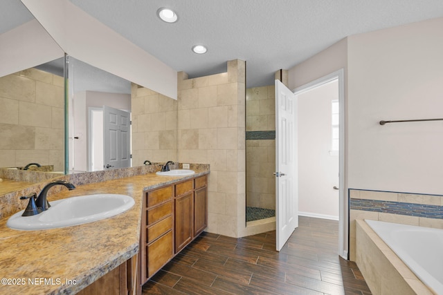 bathroom with a textured ceiling, vanity, tile walls, and independent shower and bath