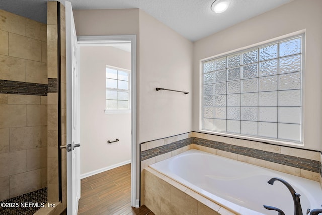 bathroom with independent shower and bath, a textured ceiling, and a wealth of natural light