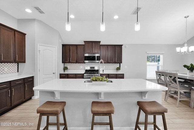 kitchen with decorative light fixtures, stainless steel appliances, and a breakfast bar area