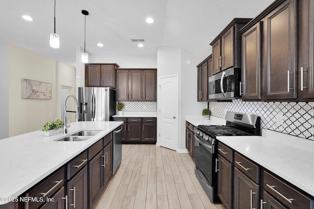 kitchen featuring hanging light fixtures, sink, stainless steel appliances, and dark brown cabinets