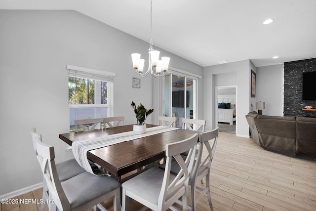 dining area featuring a notable chandelier, light wood-type flooring, and vaulted ceiling