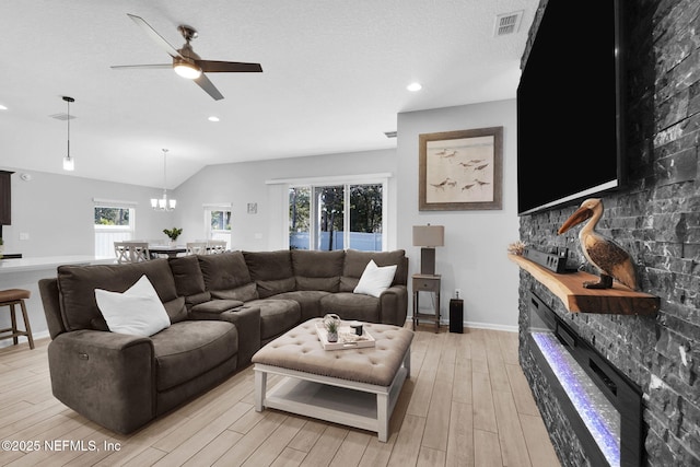 living room featuring a textured ceiling, ceiling fan with notable chandelier, light hardwood / wood-style floors, and vaulted ceiling