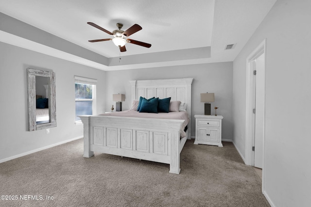 bedroom with ceiling fan, light colored carpet, and a tray ceiling