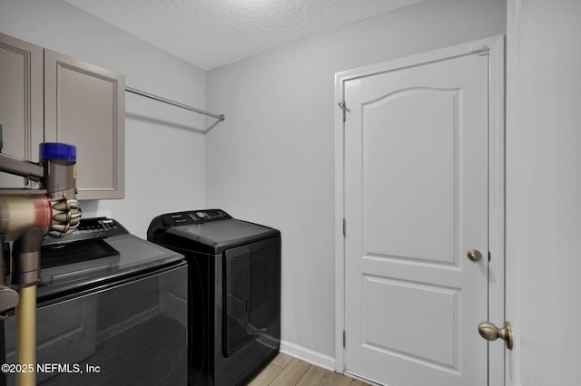 washroom with light wood-type flooring, independent washer and dryer, and a textured ceiling