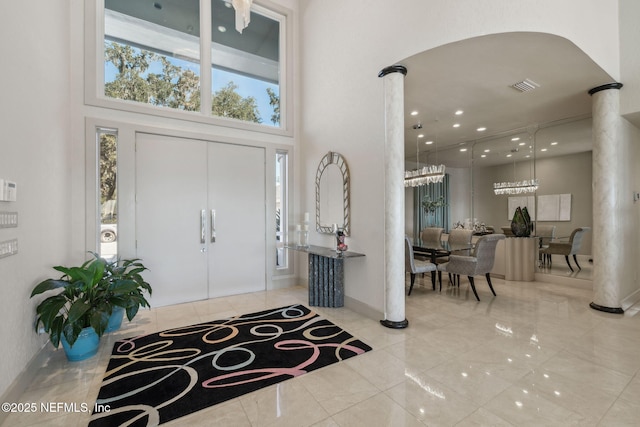 foyer with a high ceiling, a chandelier, and decorative columns