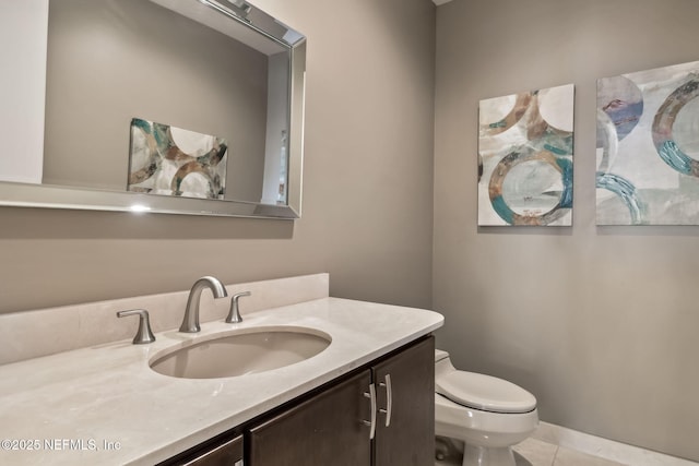 bathroom with toilet, vanity, and tile patterned flooring