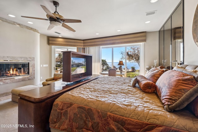 carpeted bedroom featuring ceiling fan, a fireplace, and access to outside