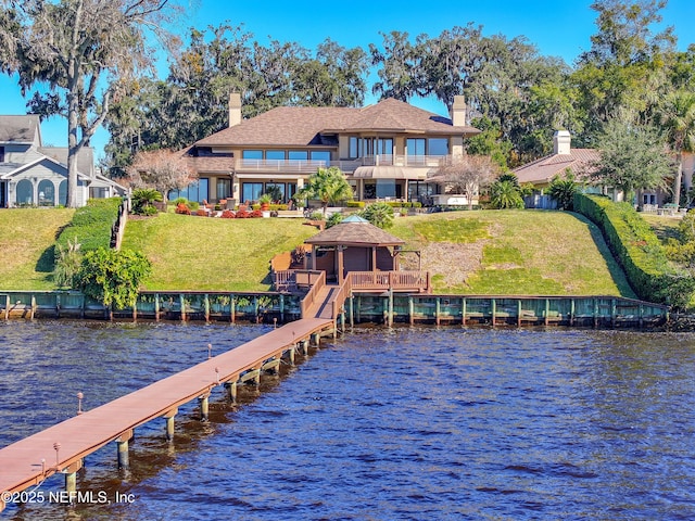 view of dock with a balcony, a gazebo, a lawn, and a water view