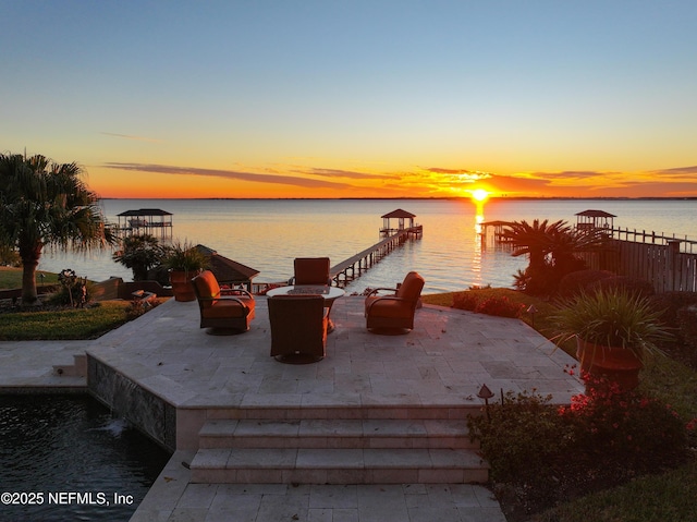 view of dock featuring a water view, a fire pit, and a patio