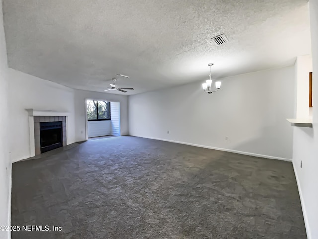 unfurnished living room featuring a textured ceiling, ceiling fan with notable chandelier, dark carpet, and a tiled fireplace