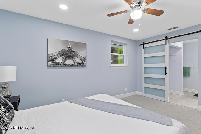 carpeted bedroom featuring ceiling fan and a barn door