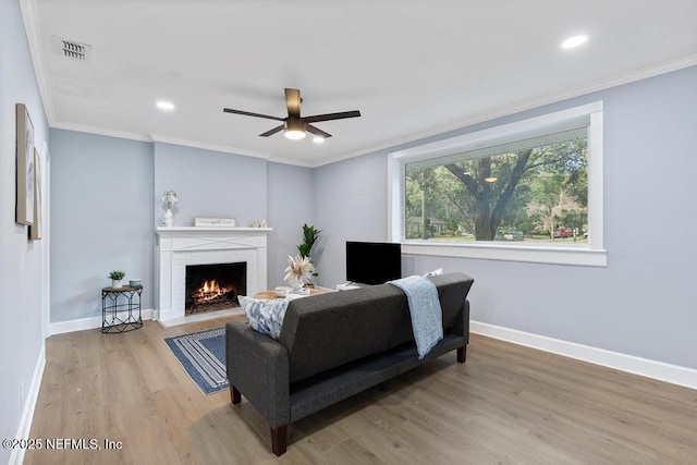 living room featuring hardwood / wood-style flooring, a brick fireplace, and crown molding