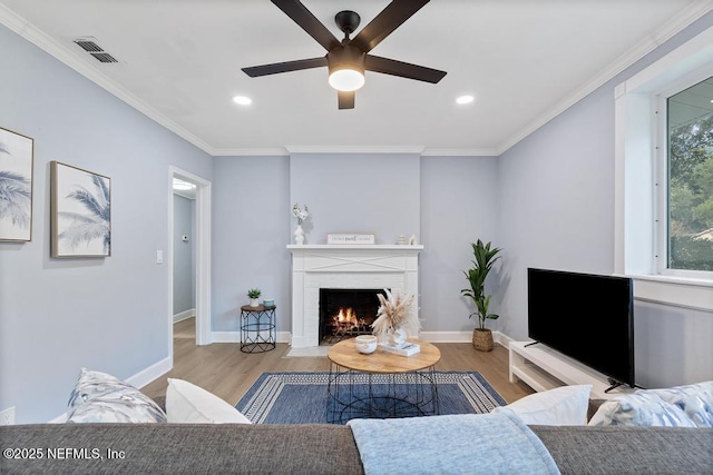 living room with ornamental molding, ceiling fan, and light hardwood / wood-style flooring