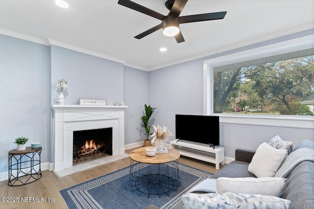 living room featuring ornamental molding, ceiling fan, a brick fireplace, and hardwood / wood-style floors