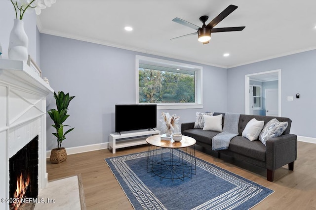 living room with hardwood / wood-style flooring, ornamental molding, a brick fireplace, and ceiling fan