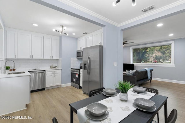 kitchen with tasteful backsplash, white cabinetry, sink, light hardwood / wood-style flooring, and stainless steel appliances