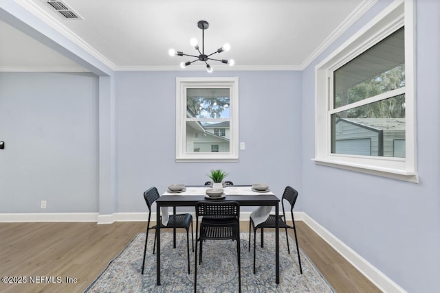 dining area with hardwood / wood-style floors, a healthy amount of sunlight, and a notable chandelier