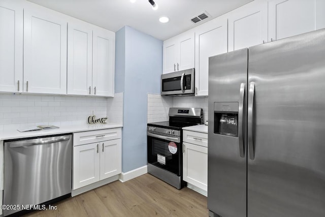 kitchen with white cabinetry, light wood-type flooring, stainless steel appliances, and tasteful backsplash