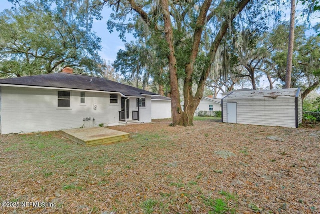 rear view of property with a deck, a shed, and a lawn