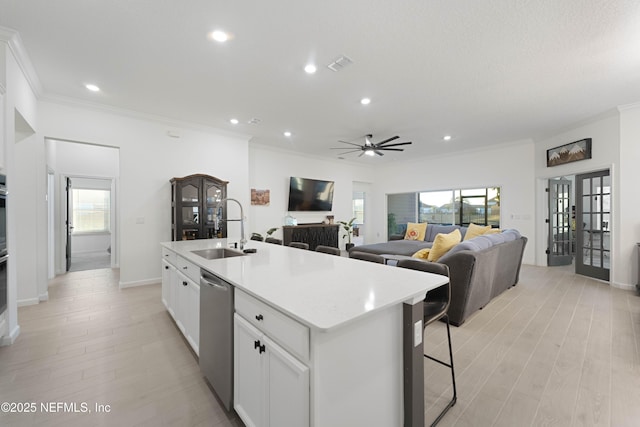 kitchen featuring sink, dishwasher, white cabinets, and a kitchen island with sink