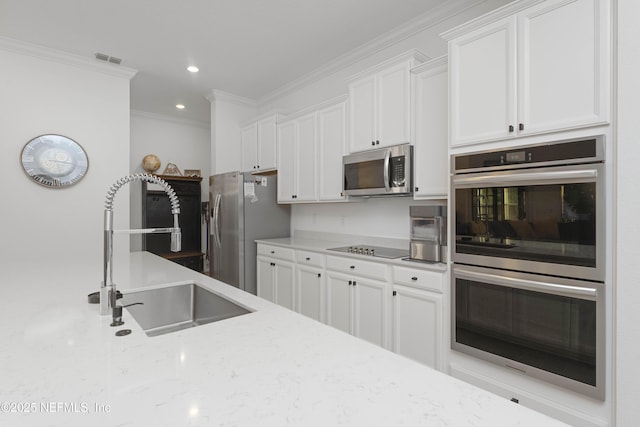 kitchen with light stone counters, stainless steel appliances, white cabinets, ornamental molding, and sink