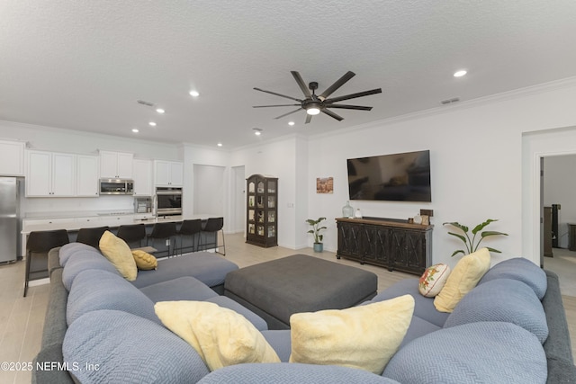 living room featuring a textured ceiling, ornamental molding, and ceiling fan