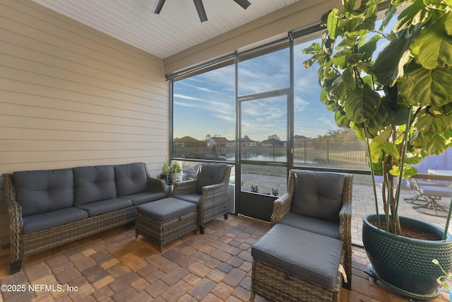 sunroom with ceiling fan and a water view