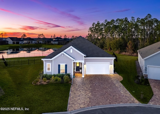 view of front of home with a yard, a garage, and a water view