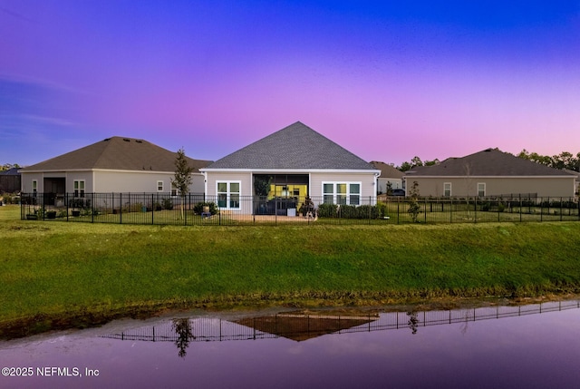 back house at dusk featuring a yard