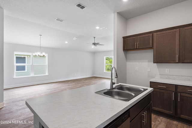 kitchen with sink, hanging light fixtures, a center island with sink, a textured ceiling, and hardwood / wood-style flooring