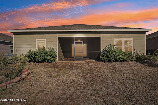 back house at dusk featuring a sunroom