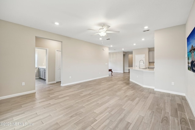 unfurnished living room with ceiling fan, sink, and light hardwood / wood-style flooring