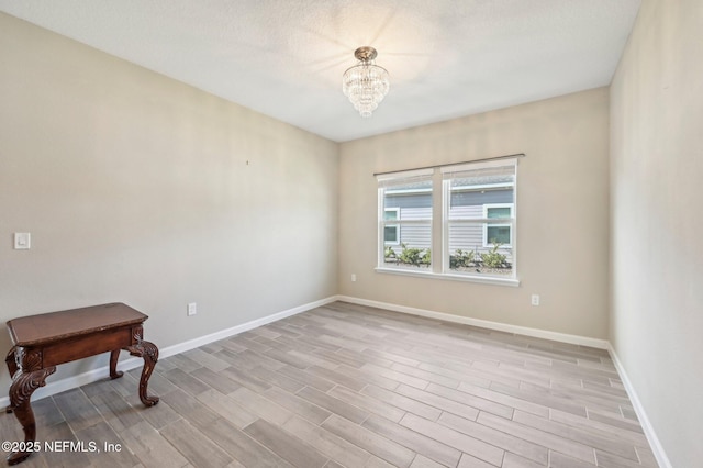 spare room with light wood-type flooring and a notable chandelier