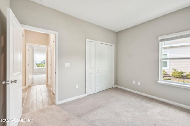 unfurnished bedroom featuring light carpet and a closet