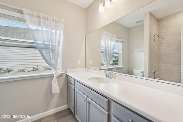 bathroom featuring hardwood / wood-style floors, vanity, toilet, and a tile shower