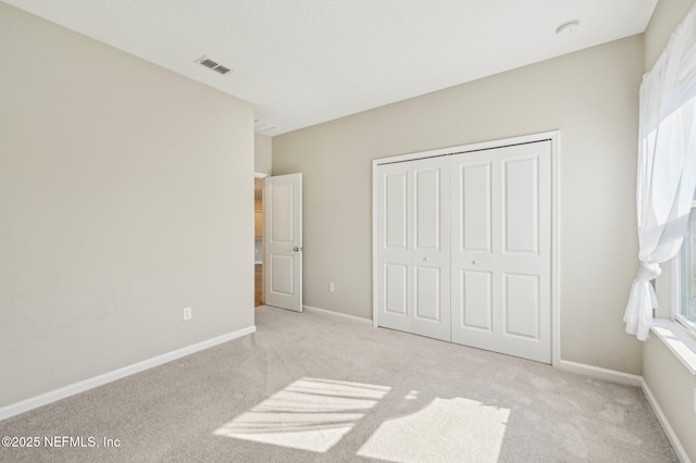 unfurnished bedroom featuring light carpet and a closet