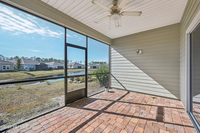 unfurnished sunroom with a water view and ceiling fan