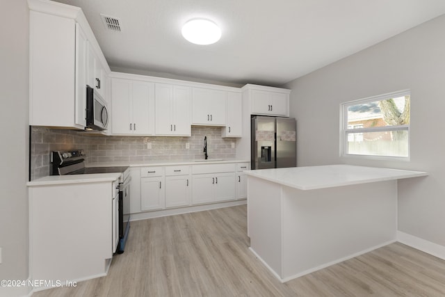 kitchen with white cabinets, sink, light hardwood / wood-style flooring, tasteful backsplash, and stainless steel appliances