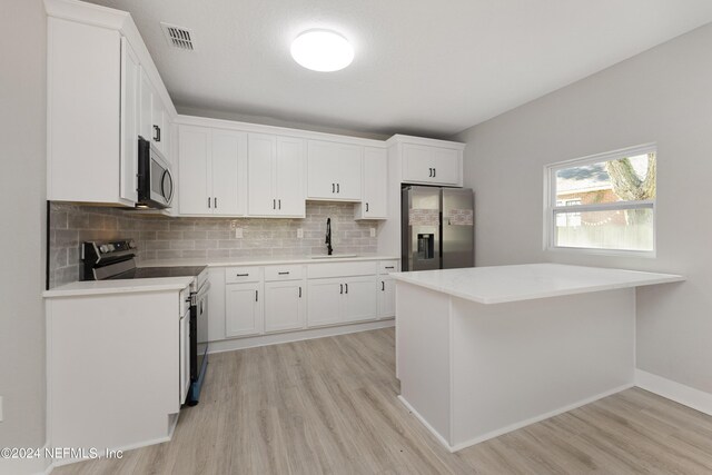 kitchen with white cabinetry, sink, tasteful backsplash, light hardwood / wood-style flooring, and appliances with stainless steel finishes