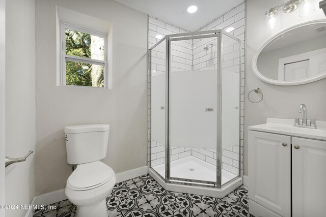 bathroom with tile patterned floors, vanity, an enclosed shower, and toilet